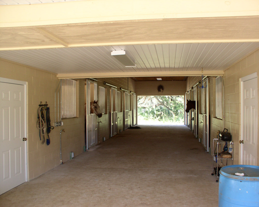 Horse stall aisle way, featuring aluminum coolbreeze sliding doors.