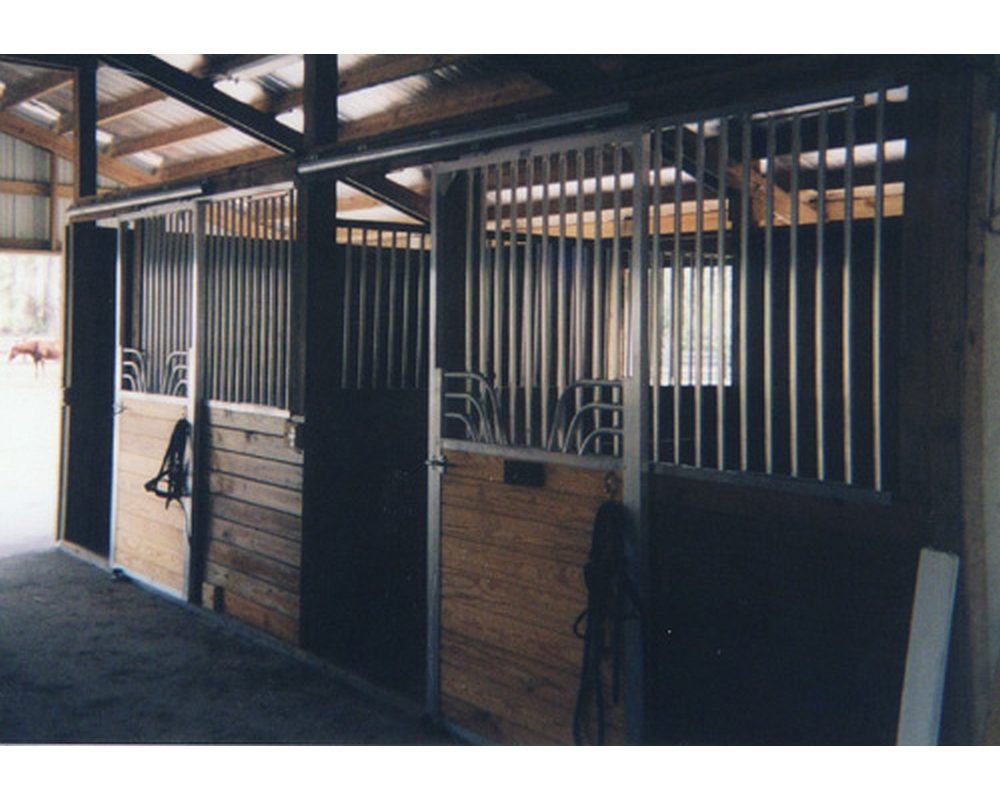 Horse stall fronts with tongue and groove lumber and sliding stall doors.