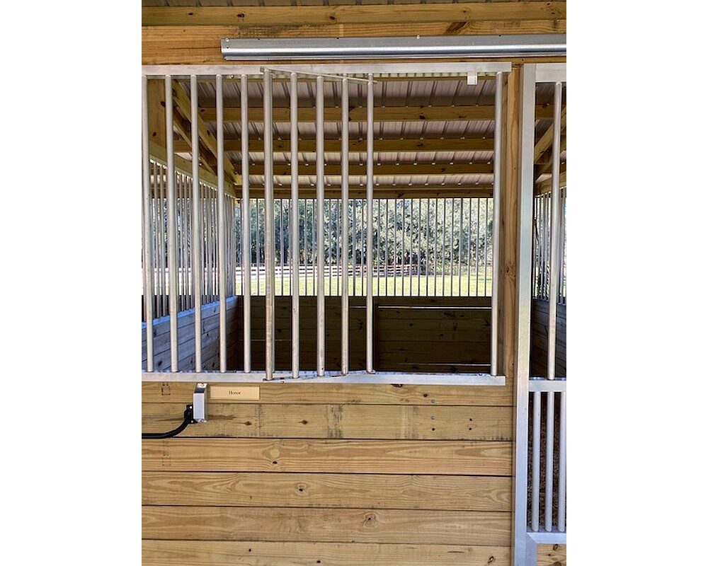Horse stall front grill with feeder access door in open position.